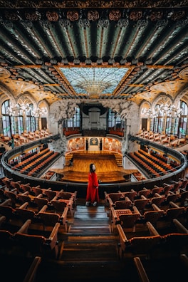 A wide shot of the concert hall bathed in red and white tones, capturing the cultural ambiance.