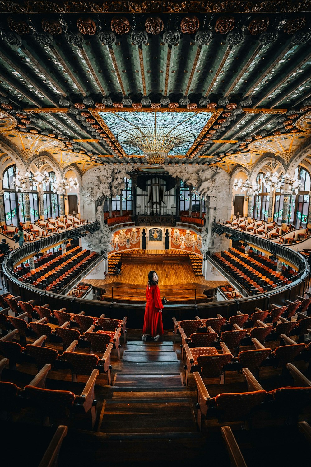 a woman in a red dress sitting in a large auditorium