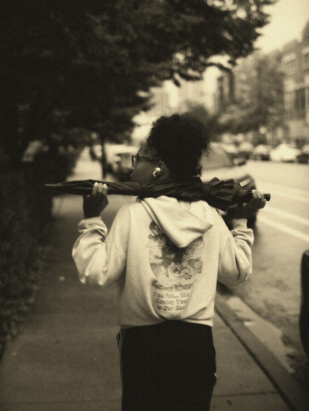 a woman walking down a sidewalk with a gun in her hand