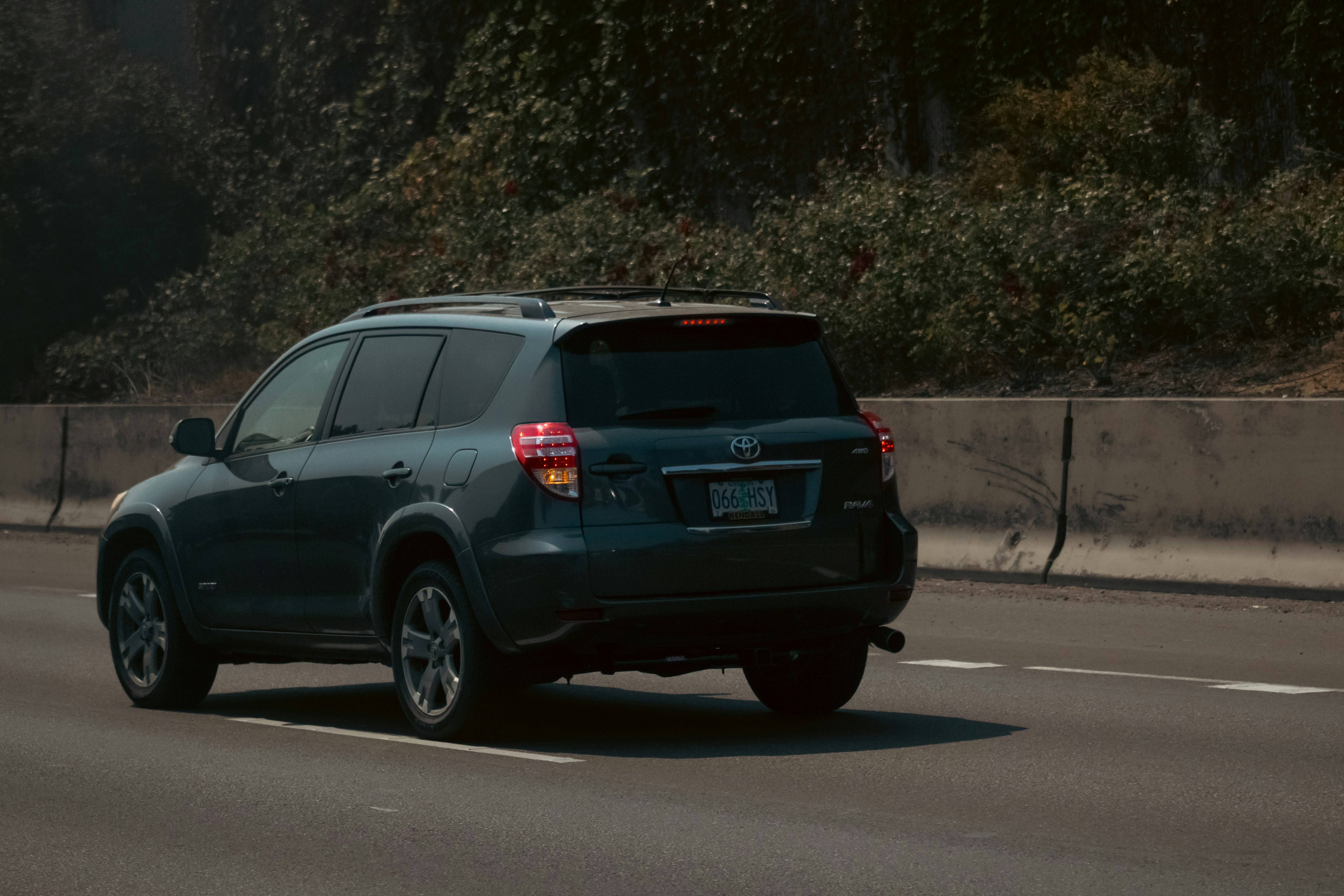 Um SUV cinza dirigindo por uma estrada ao lado de uma floresta