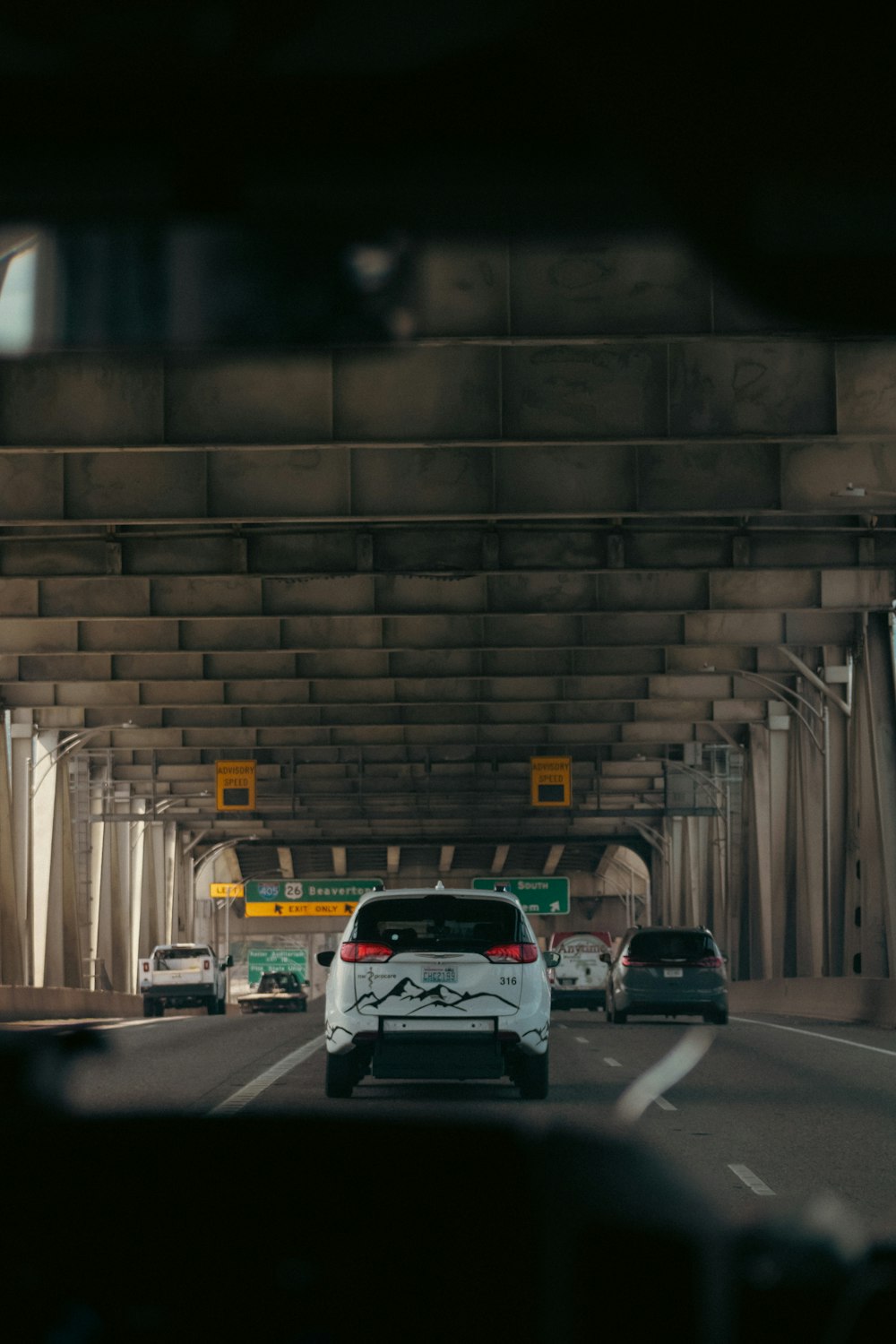 a car driving down a street under a bridge