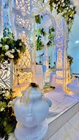 An elegant wedding mandap set against intricate palace architecture with rich red and gold drapes.