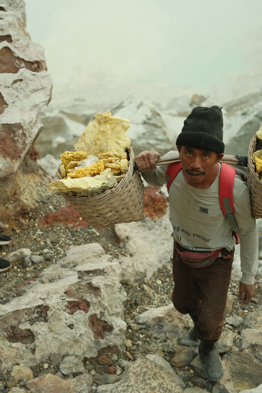 a man carrying two baskets of food on his back