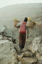 a man with two baskets walking up a mountain