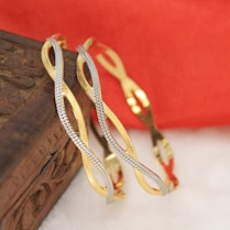a pair of gold and silver bracelets sitting on top of a book