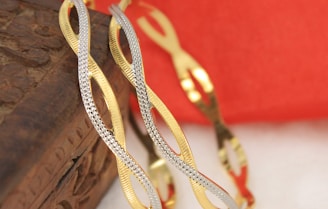 a pair of gold and silver bracelets sitting on top of a book