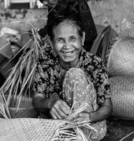 A smiling artisan weaving hemp fiber baskets in a sunlit studio.