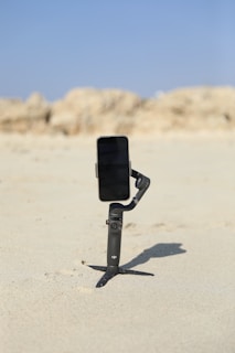 A content creator setting up a mobile vlogging rig with a smartphone and stabilizer near the beach