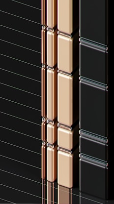 A series of glossy, rectangular tiles arranged vertically with a metallic finish. The tiles are colored in gold, copper, and black, creating a sleek and modern appearance. The surface reflects light, highlighting the smooth texture and polished edges.