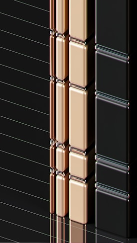 A series of glossy, rectangular tiles arranged vertically with a metallic finish. The tiles are colored in gold, copper, and black, creating a sleek and modern appearance. The surface reflects light, highlighting the smooth texture and polished edges.