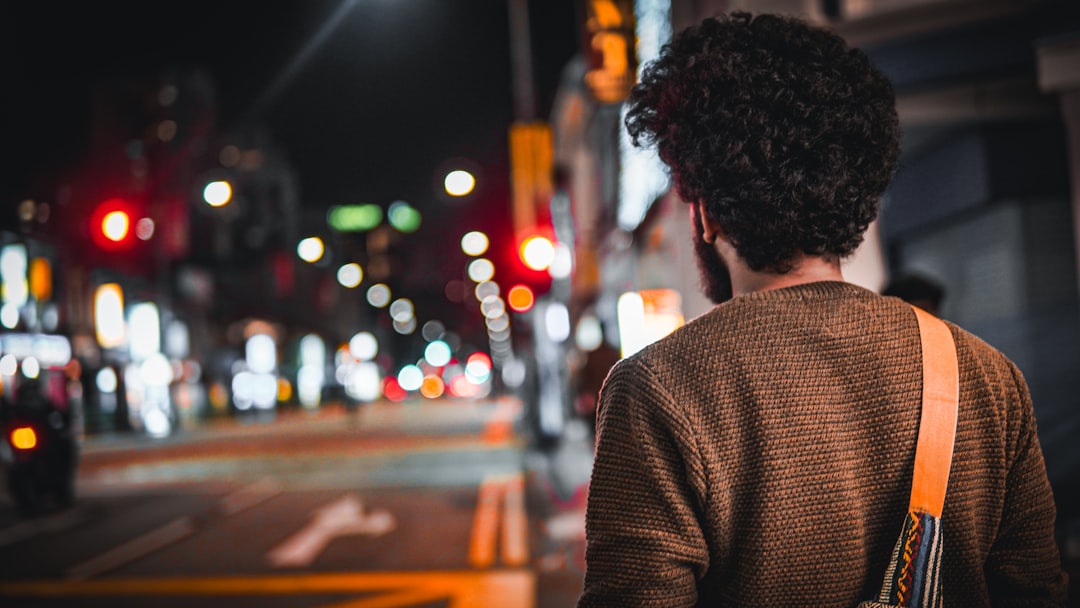 a person standing on a city street at night, Lost in the Urban Symphony: A Glimpse of Reflections and Dreams