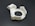 A white, circular 3D-printed plastic object with a cutout resembling a gear or mechanical part. It has various geometric shapes and indents on its surface, placed on a dark background.