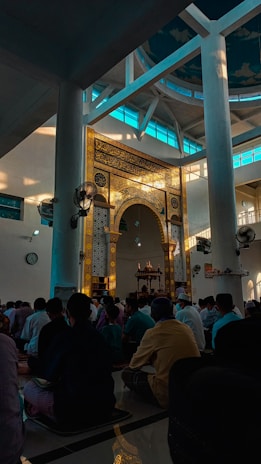 A group of happy students praying together in the school mosque with sunlight streaming in.
