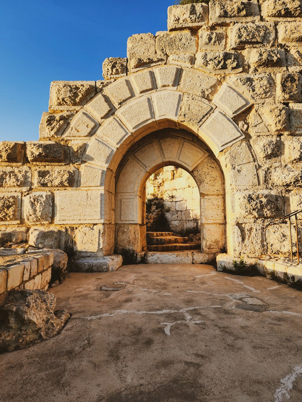 a stone archway in a stone wall with a blue sky in the background