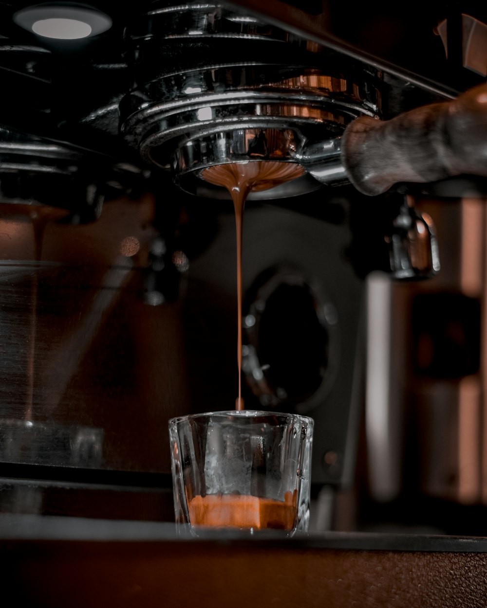 a cup of coffee being poured into a coffee machine