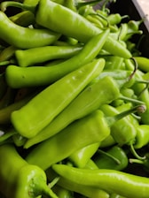 Close-up of fresh green chilies glistening with morning dew.
