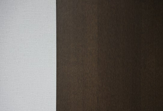 A simple vertical composition with two distinct textures and colors. The left side features a light grey woven fabric, while the right side displays a rich, dark brown wooden texture.