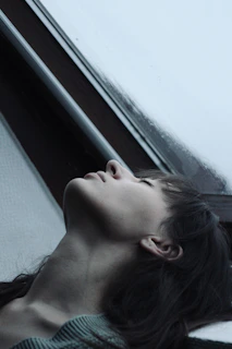 Oliver Oli in a reflective pose, seated next to a window with soft natural light