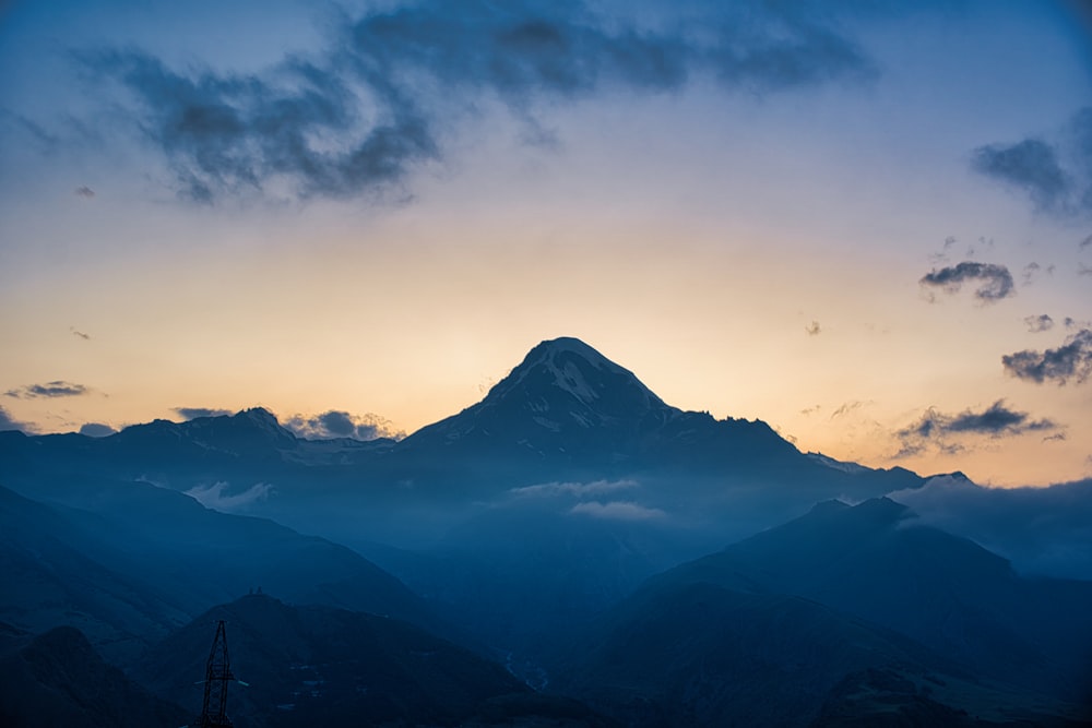 a view of a mountain at sunset with clouds