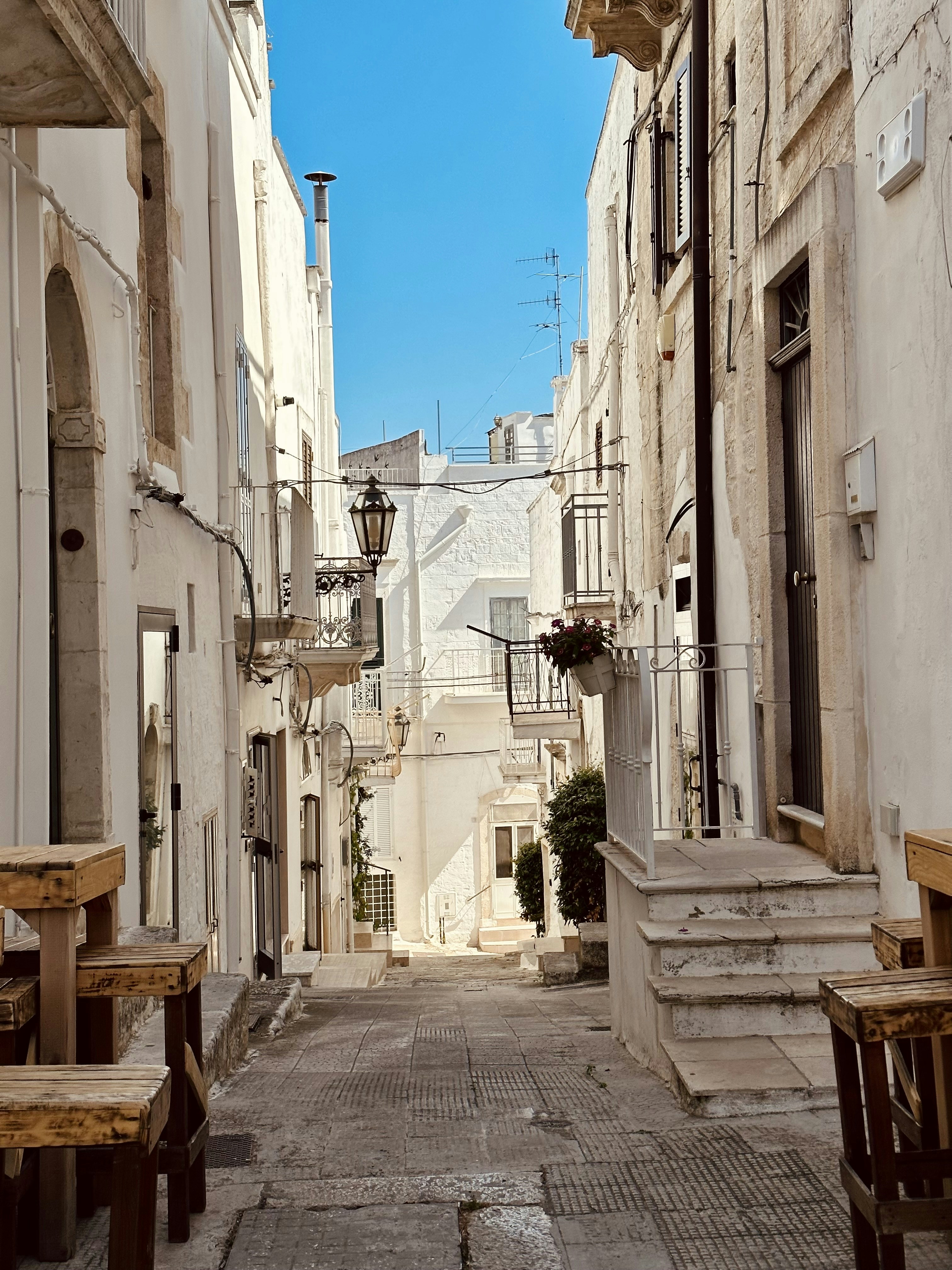 a narrow alley way with benches and tables