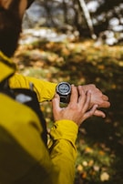 Person wearing a smartwatch while jogging in a park at sunrise.