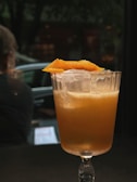 A sleek cocktail glass with a bright, refreshing drink garnished with citrus.