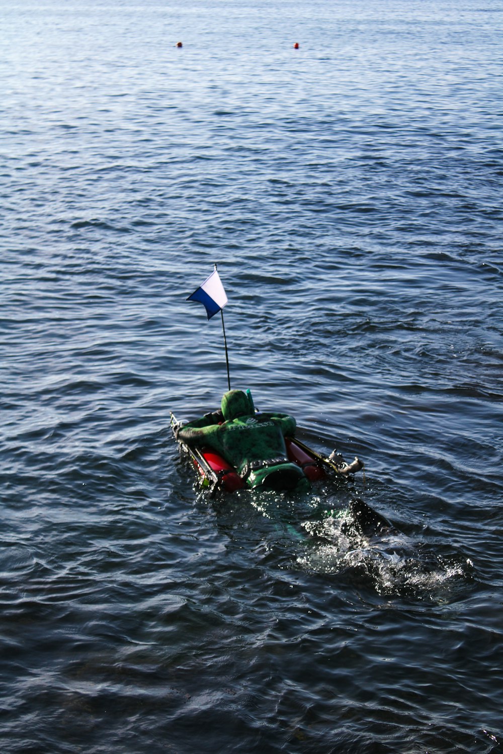 a small boat with a flag in the middle of a body of water