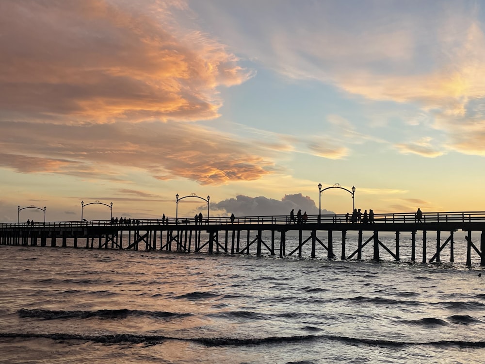 um píer com pessoas em pé ao pôr do sol