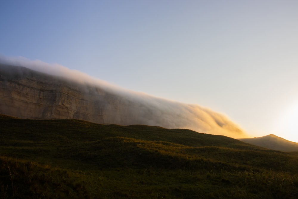 the sun is shining behind the clouds in the mountains