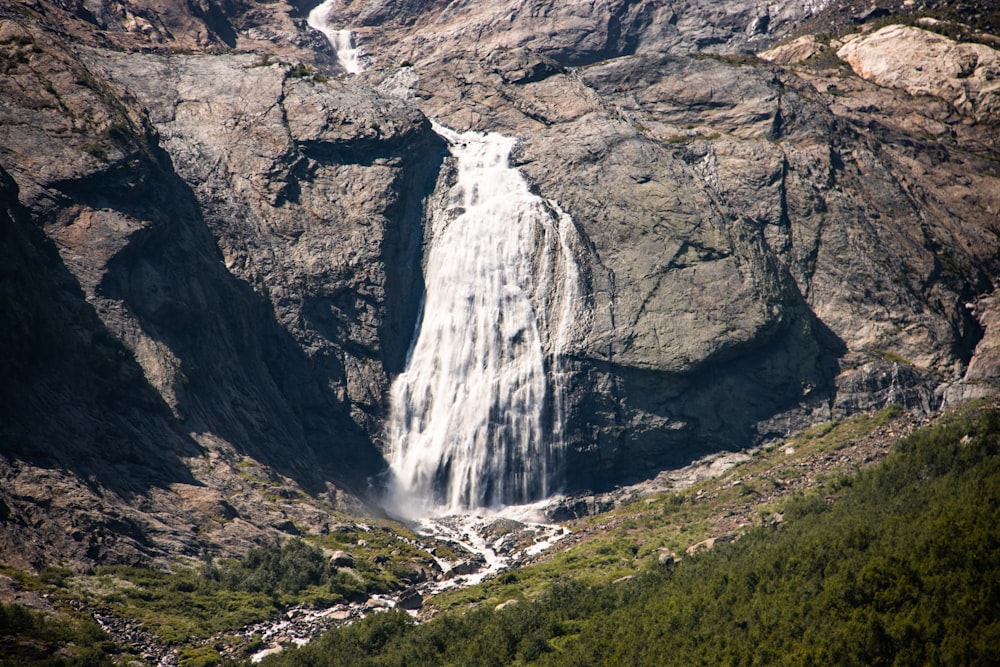 a very tall waterfall in the middle of a mountain