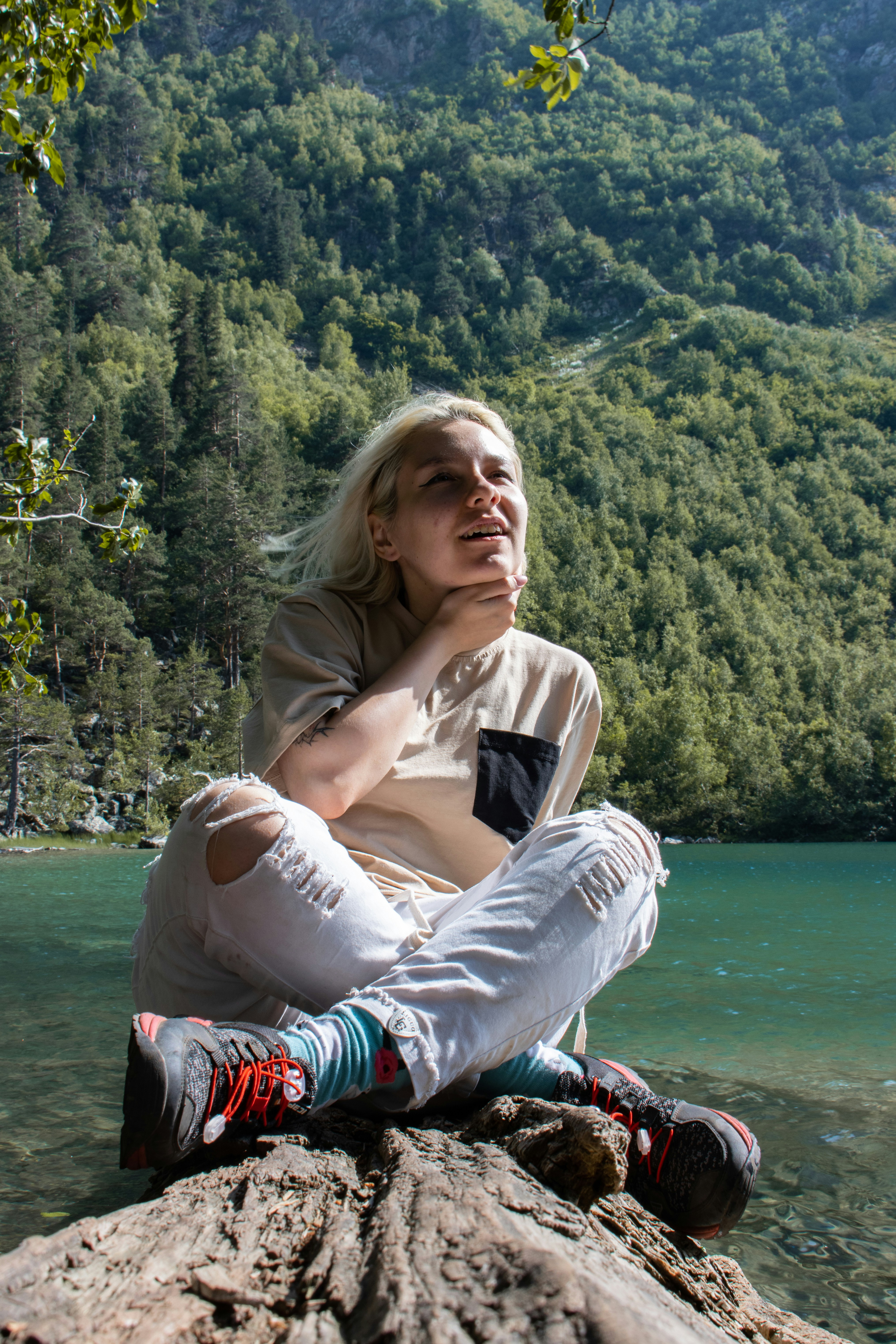 A woman sitting on top of a rock next to a lake photo – Free Active ...