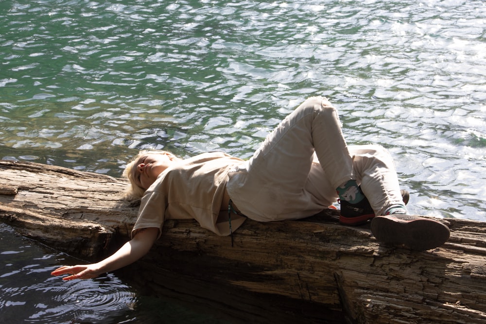 une personne allongée sur une bûche dans l’eau