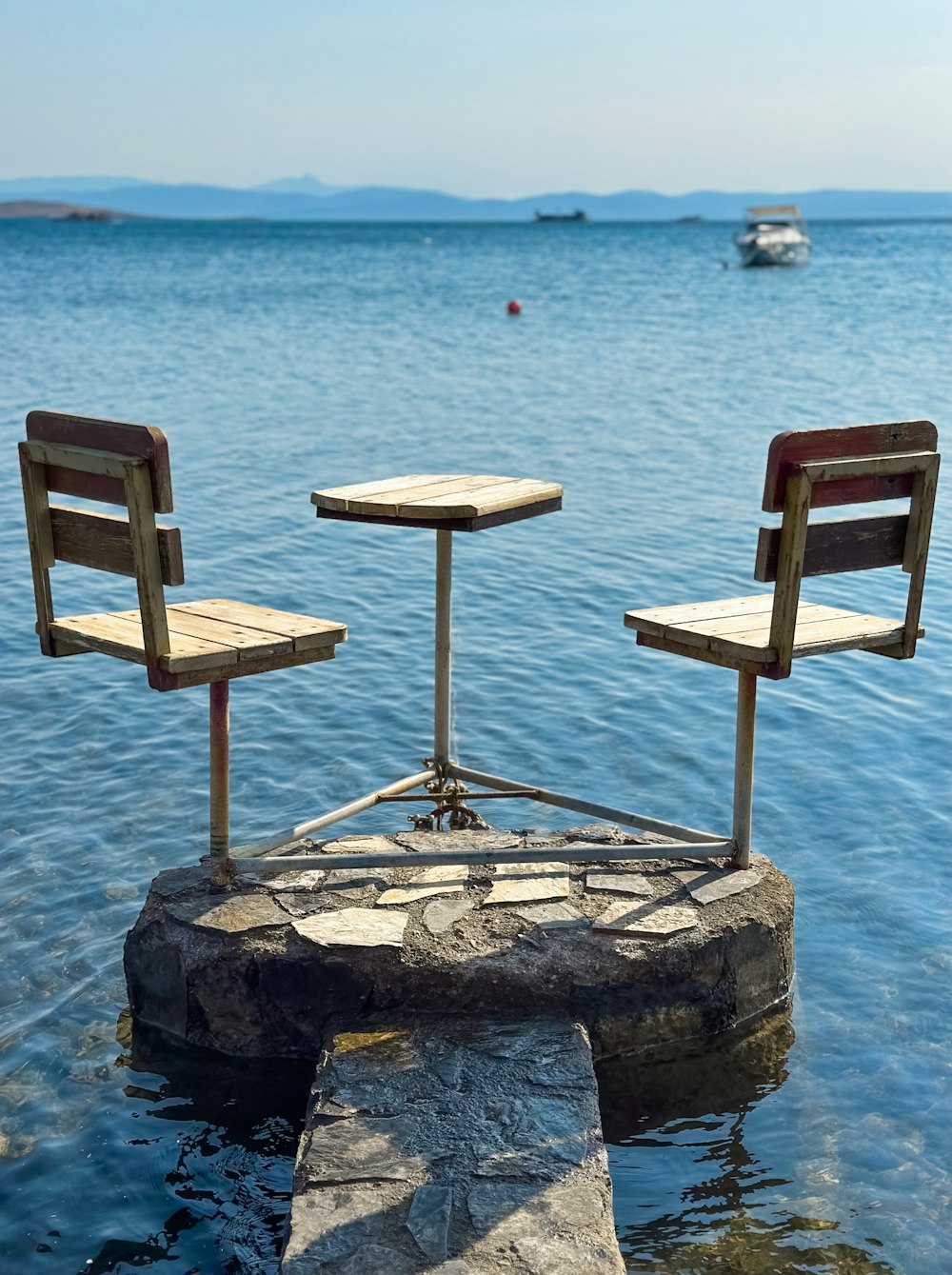 two chairs sitting on top of a rock in the water