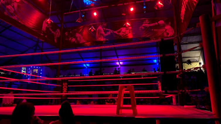 A sleek neon-lit boxing ring with electric blue and purple accents, capturing the intensity of a night fight.