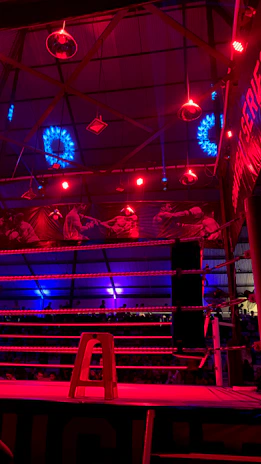 Wide-angle photo of a packed arena with bright lights illuminating a kickboxing match.