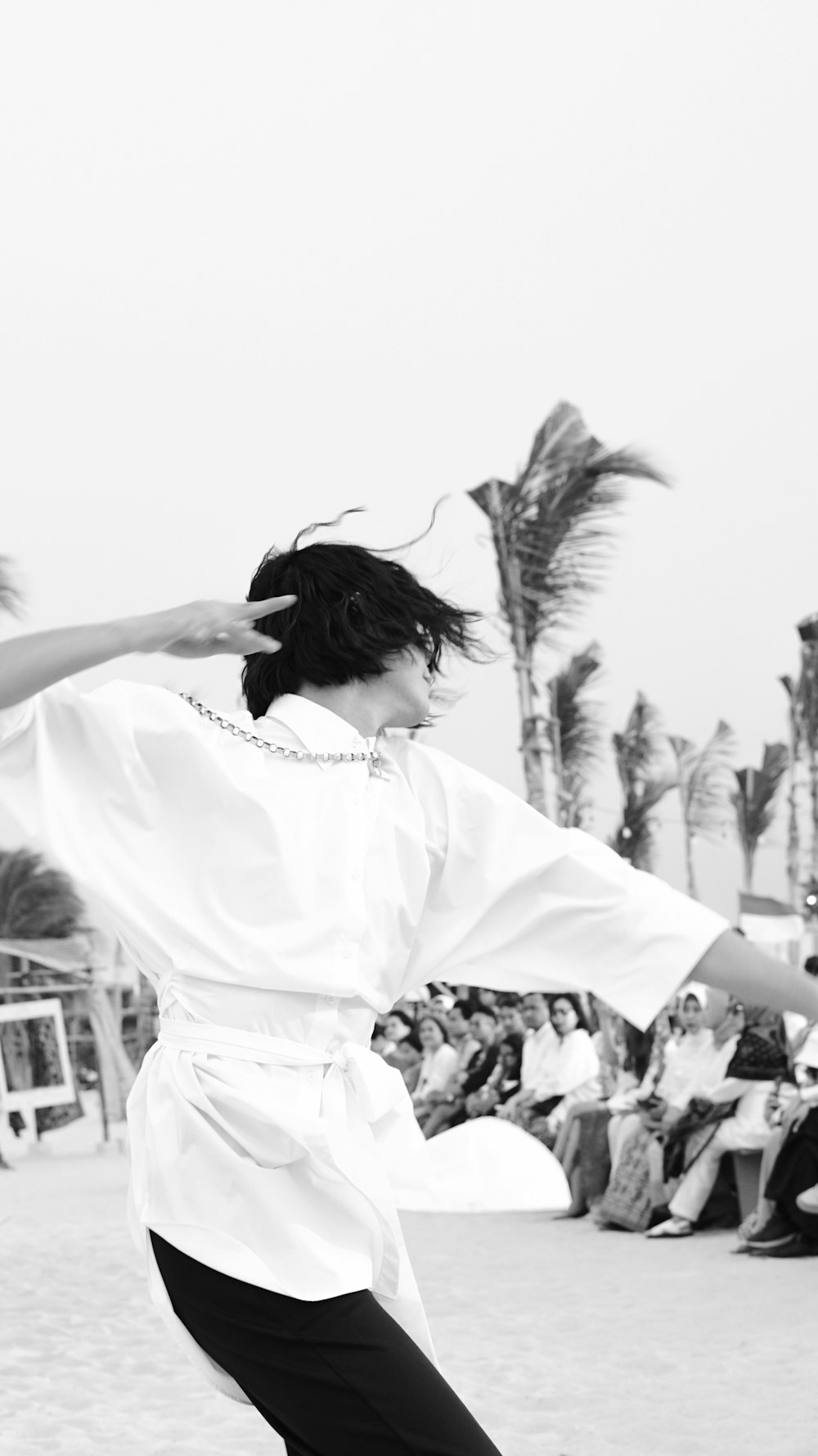 a woman in a white shirt is dancing on the beach