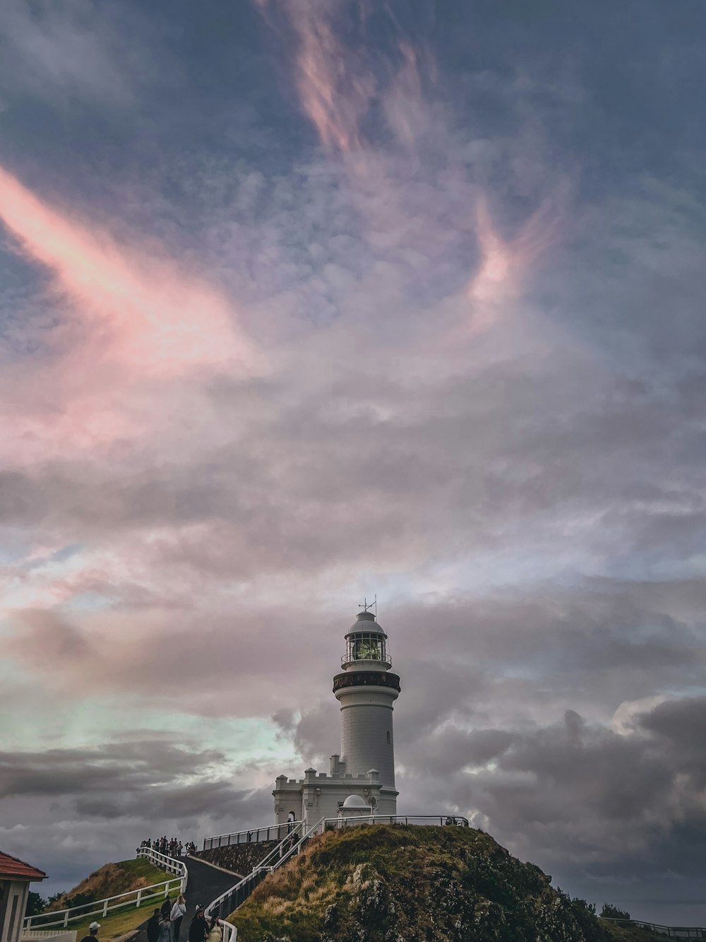 a lighthouse on top of a hill under a cloudy sky