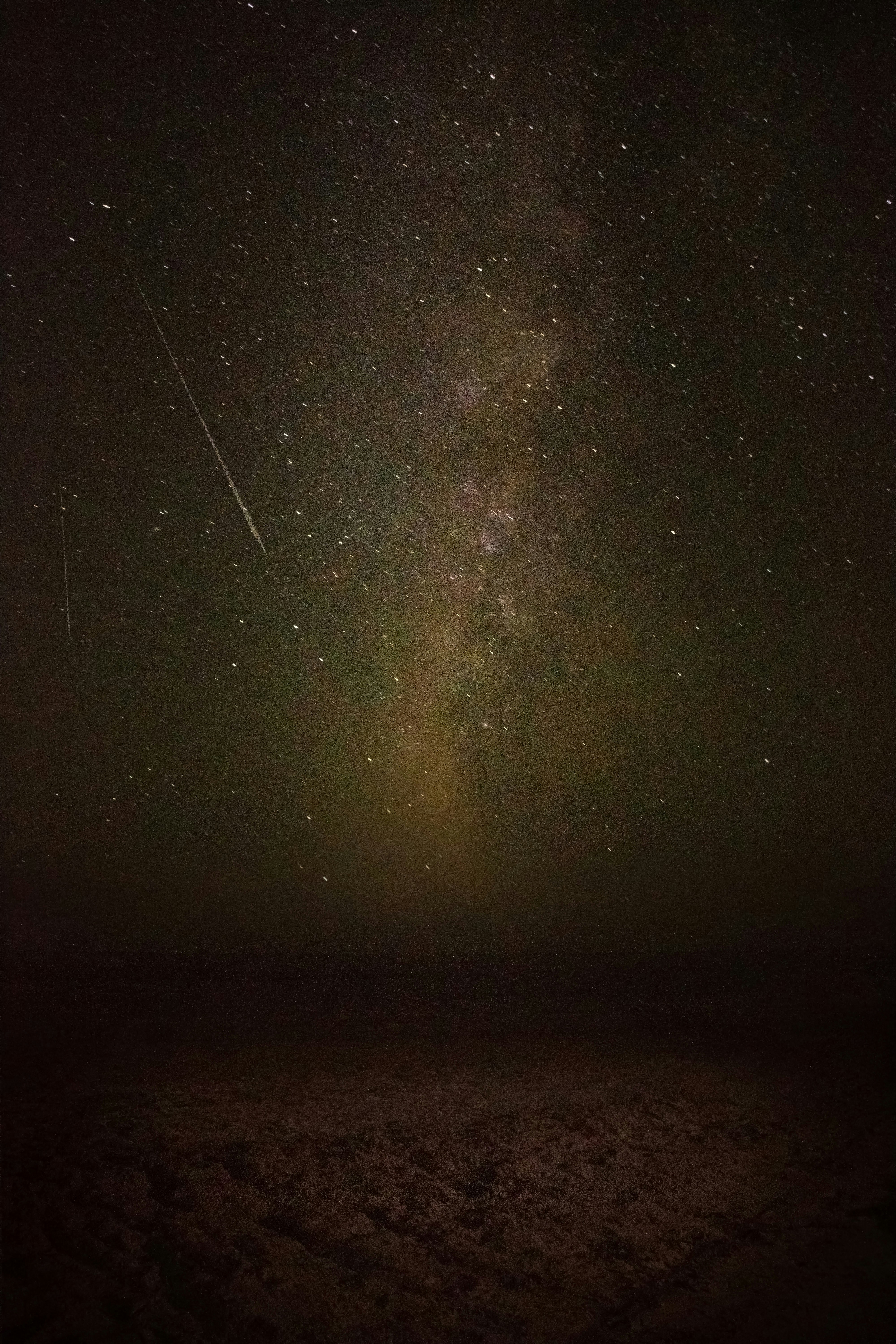 Meteor shower streaks across dark night sky over desert, dramatic wide angle view, stars and shooting stars