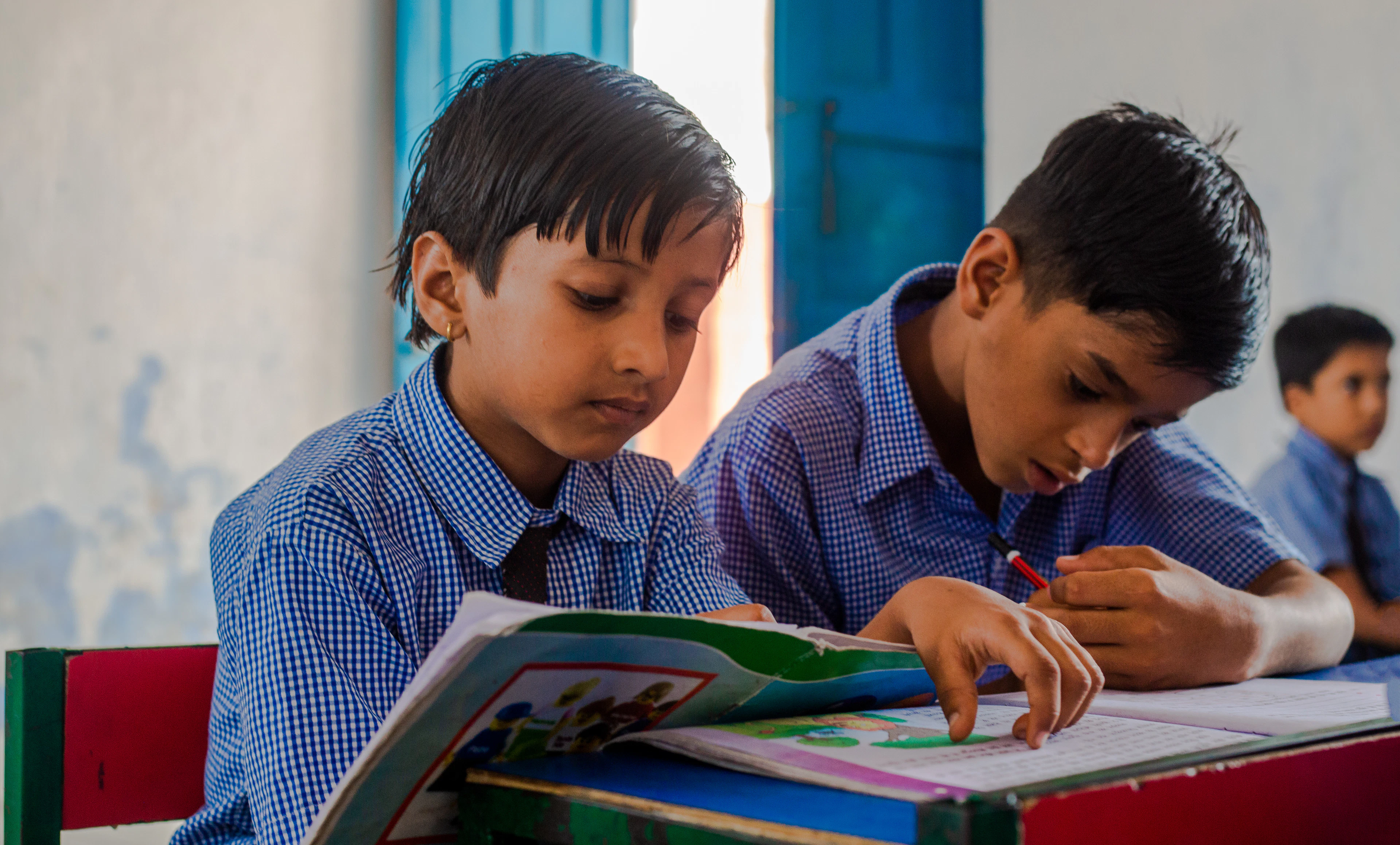 Two boys reading a book at a desk