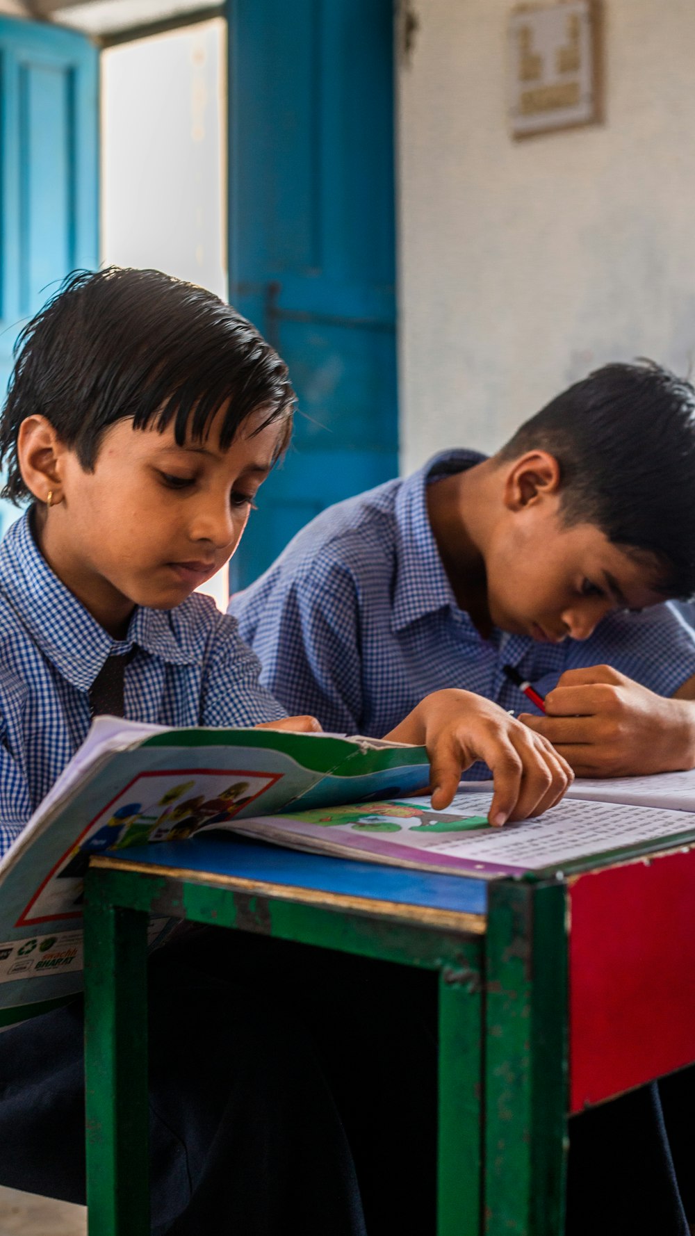 Dos niños sentados en un escritorio con un libro