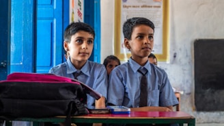 two young boys sitting at a desk in a classroom