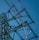 Several workers wearing safety gear are climbing a large metal lattice tower, which is possibly an electricity pylon. They use harnesses and ladders under a clear blue sky.