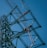 Several workers wearing safety gear are climbing a large metal lattice tower, which is possibly an electricity pylon. They use harnesses and ladders under a clear blue sky.