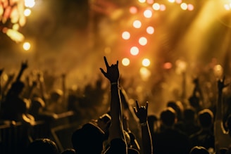 People cheering and raising hands in front of a glowing stage with electric blue accents