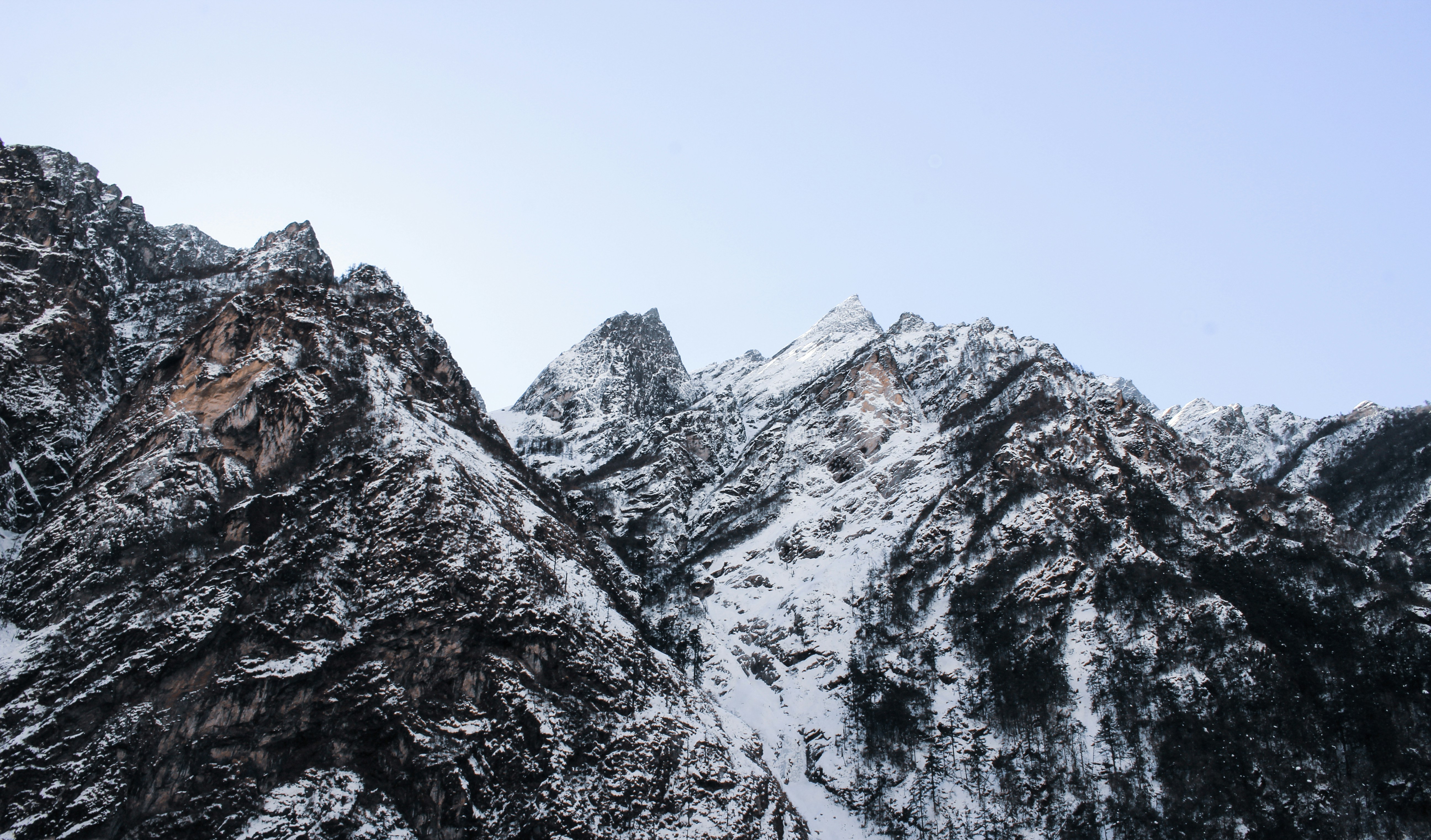 a mountain range covered in snow under a blue sky