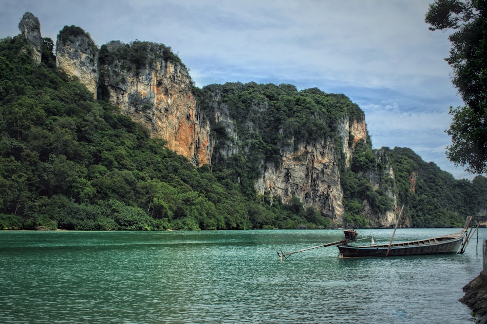 a boat floating on top of a lake next to a mountain