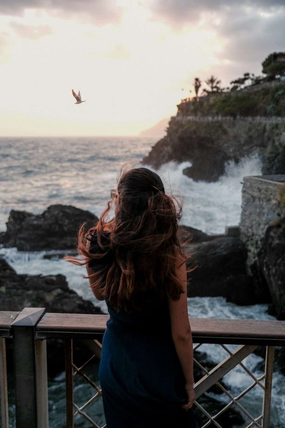 a woman standing on a balcony looking at the ocean