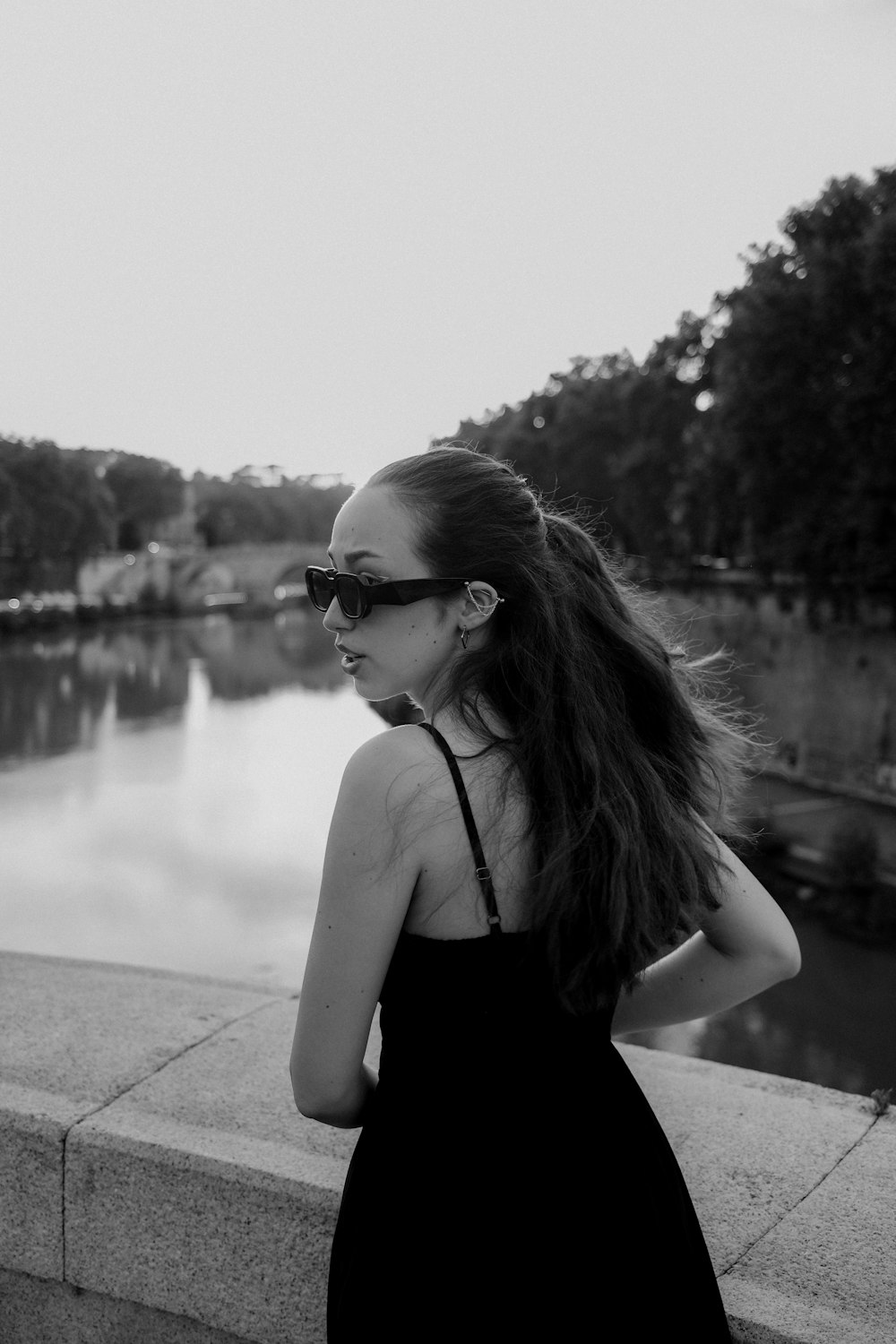 a woman in a black dress is looking at the water