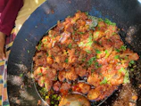 A steaming pot of simmering curry with fresh herbs on the kitchen stove.