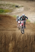 A group of dirt bike riders racing on a rugged outdoor track.
